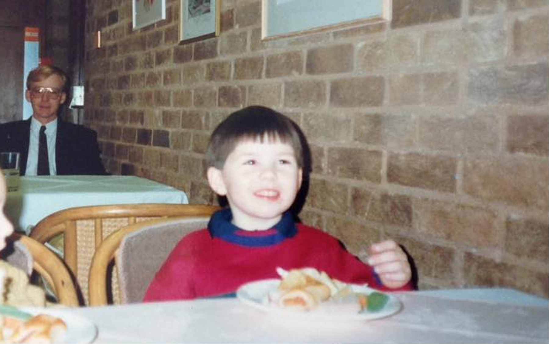The author aged five years old, grinning, he is sat at a table next to another child.